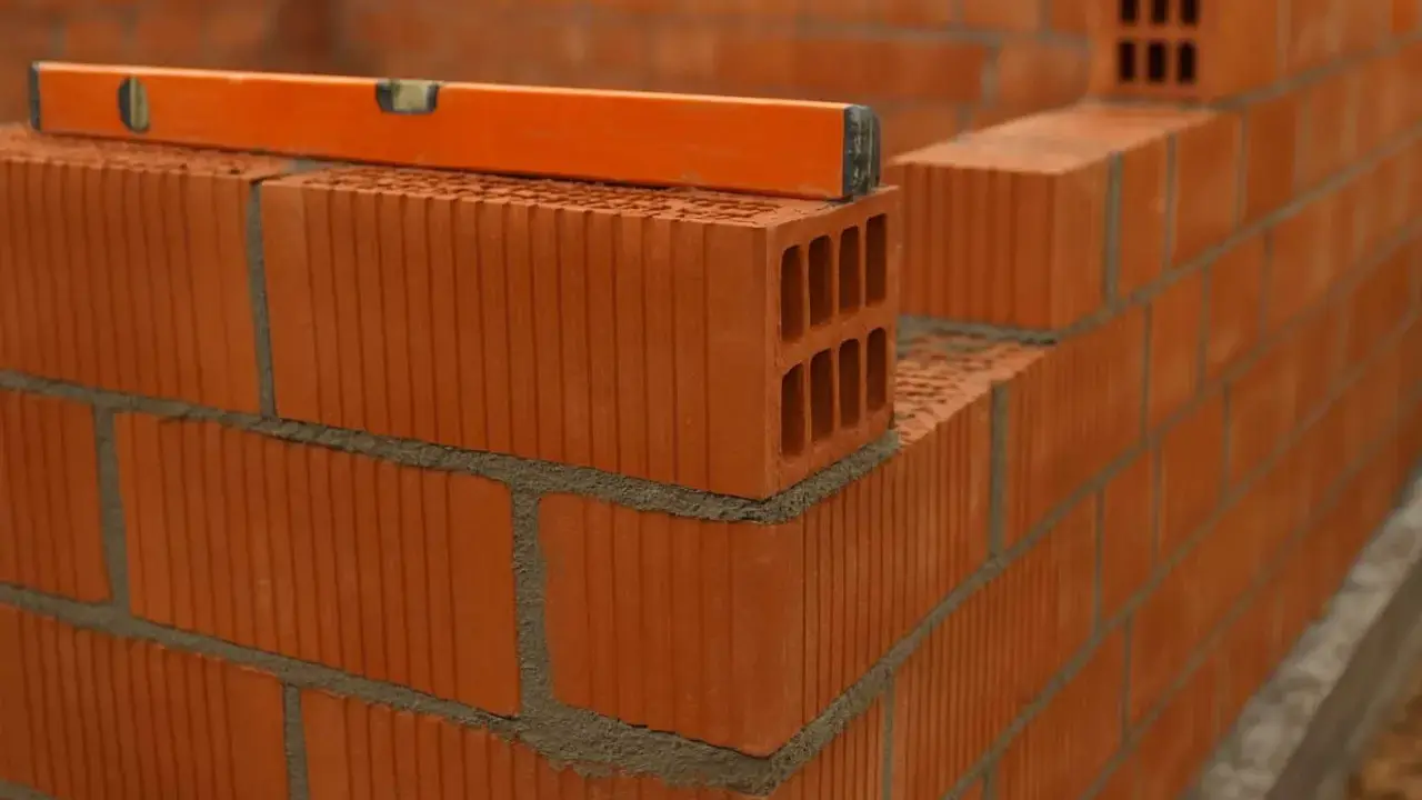 Nivel de burbuja sobre ladrillos huecos, mostrando la construcción de varios tipos de tabiques interiores.