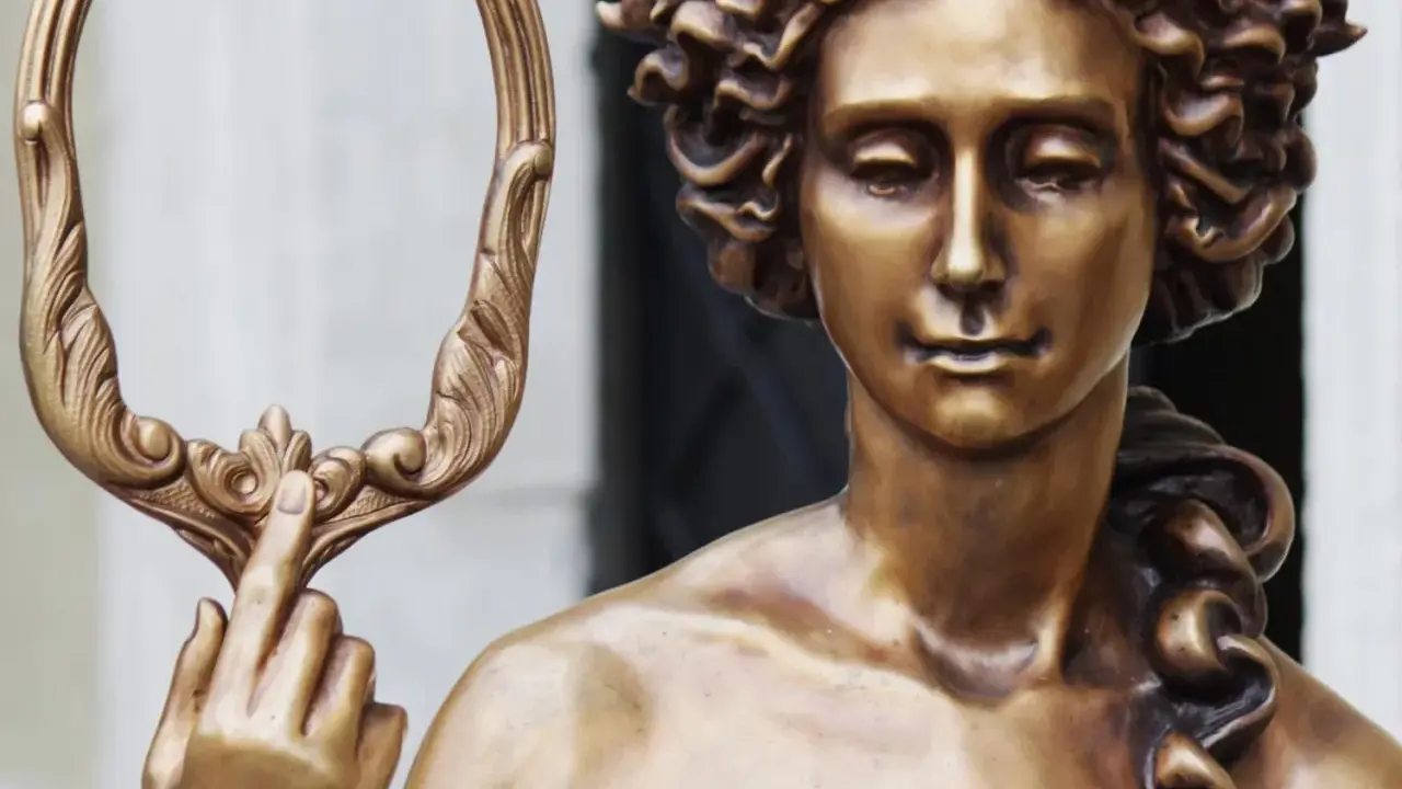 Bronzestatue der Aphrodite, die einen verzierten Spiegel hält. Ihr lockiges Haar und ihr sanfter Blick unterstreichen ihr klassisches Aphrodite-Aussehen.