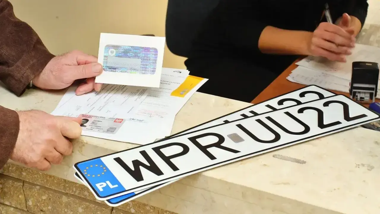 Nowe rejestracje samochodowe leżą na ladzie urzędu. Klient pokazuje dokumenty do rejestracji pojazdu.