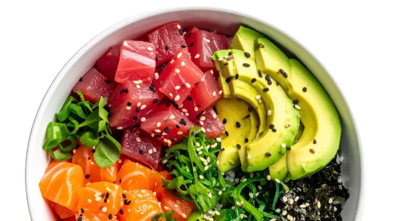 Un bol de poke coloré avec du thon, du saumon, de l'avocat et des algues, prêt à être nappé d'une délicieuse sauce poke bowl.