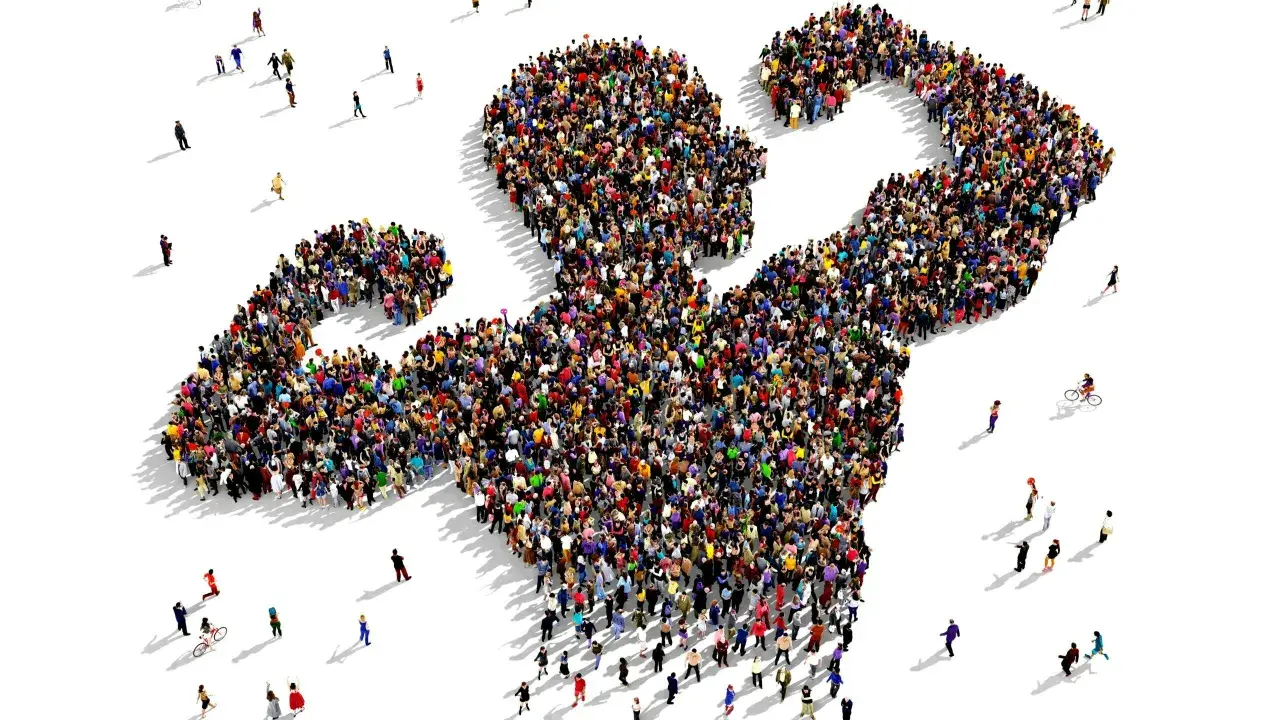 Een grote groep mensen vormt de gestalte van een gespierde arm, wat de kracht van de massa symboliseert. Dit beeld roept vragen op over wat is populisme en hoe de massa wordt gemobiliseerd.