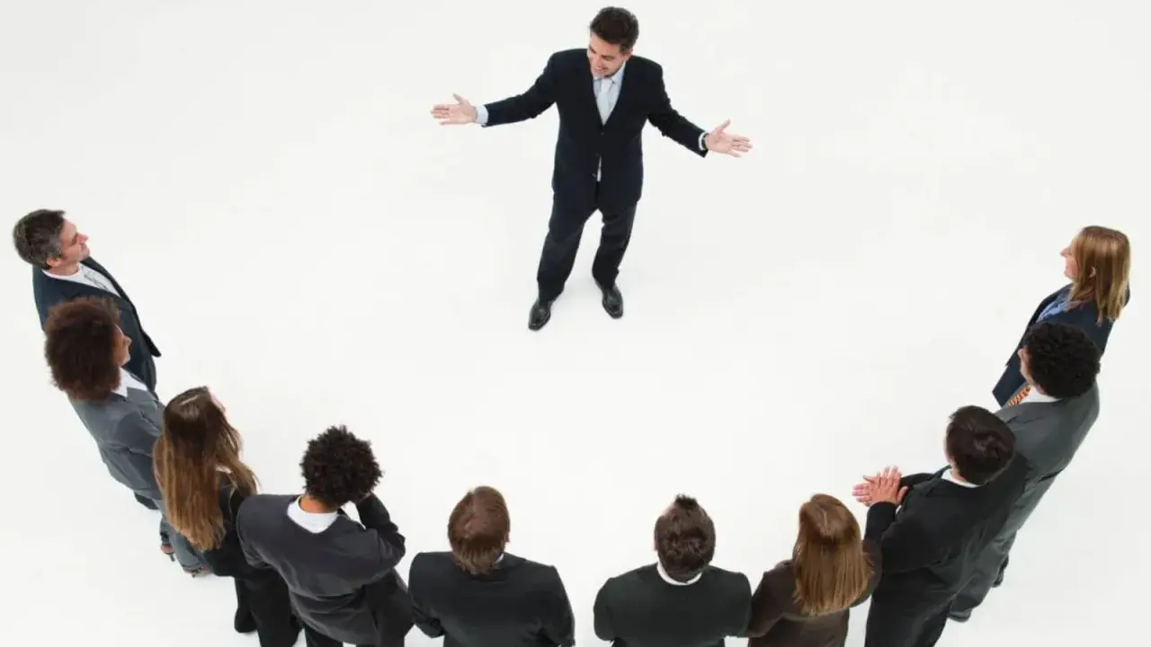 Un líder inspira a su equipo. Un grupo de personas en círculo escuchan atentamente a un hombre que demuestra master liderazgo y gestión de equipos.