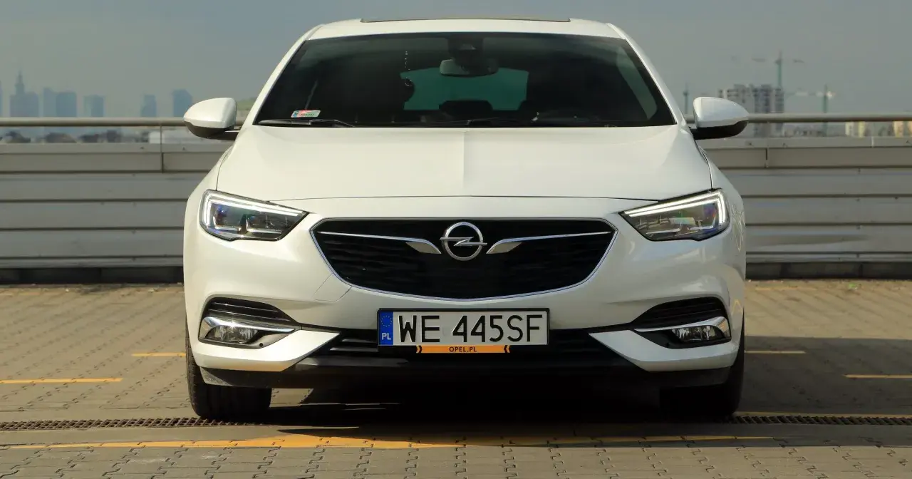 Biały Opel Insignia 2.0 Turbo z polskimi tablicami WE 445SF zaparkowany na dachu.