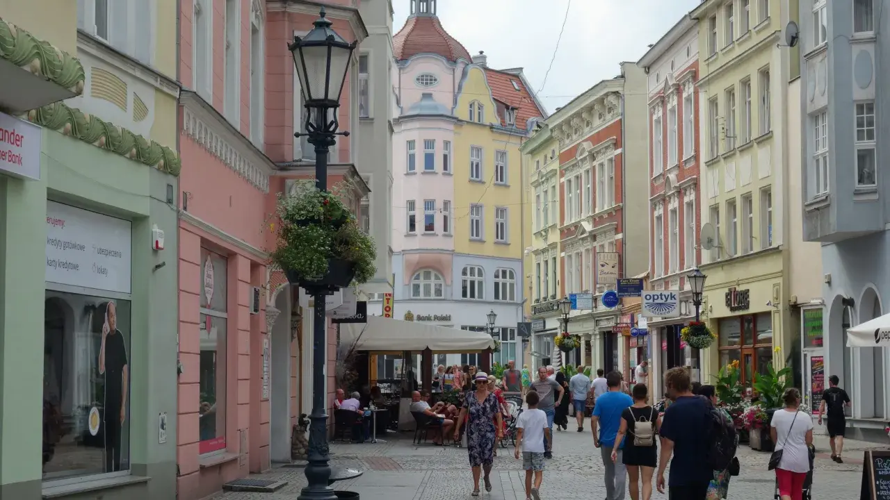 Spacer po urokliwej uliczce z kolorowymi kamienicami, idealne miejsce na zielona góra atrakcje na weekend. Ludzie spacerują, siedzą w kawiarniach.