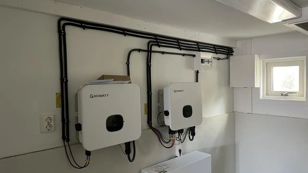 Två Growatt-växelriktare och en batteribank för solceller monterade på en vägg. Kablar dras snyggt längs väggen.