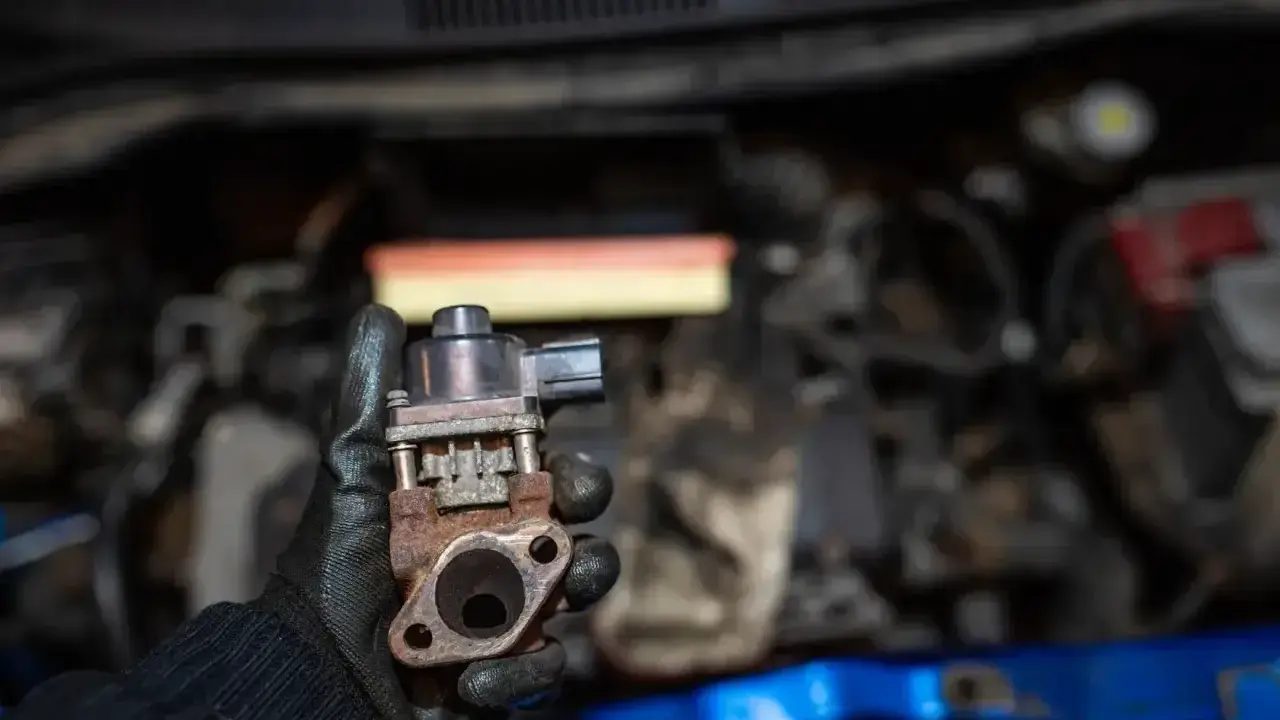 Zardzewiały zawór EGR w dłoni mechanika, gotowy do montażu w silniku.