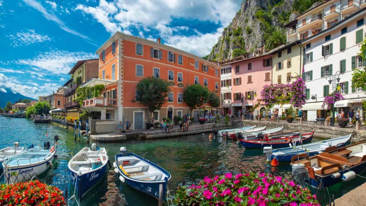 Colorate case sul lungolago di Limone sul Garda, con barche ormeggiate e fiori vivaci. Un luogo incantevole da scoprire, perfetto per capire cosa visitare a Limone sul Garda.
