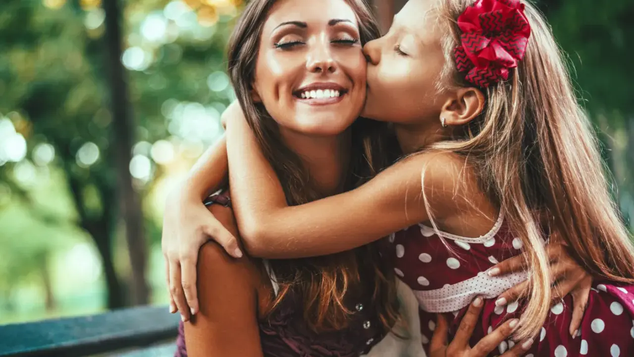 En flicka ger sin mamma en kyss på kinden. En vacker bild av kärlek och **compassion svenska**.