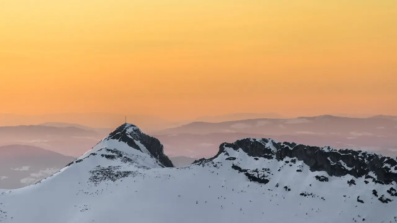 Giewont zimą o zachodzie słońca. Ośnieżone szczyty Tatr w odcieniach pomarańczy i różu.