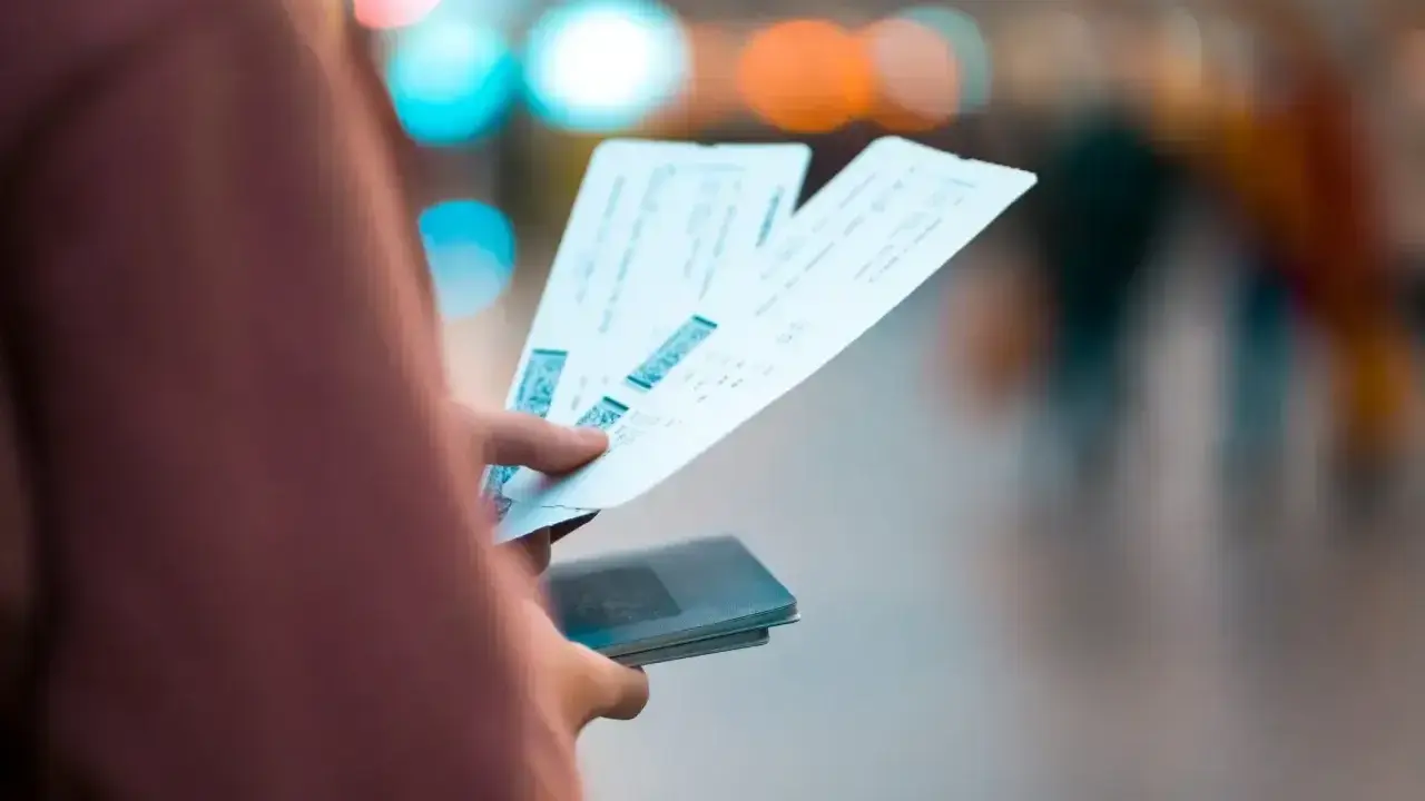 Dłoń trzymająca kilka biletów lotniczych i paszport.