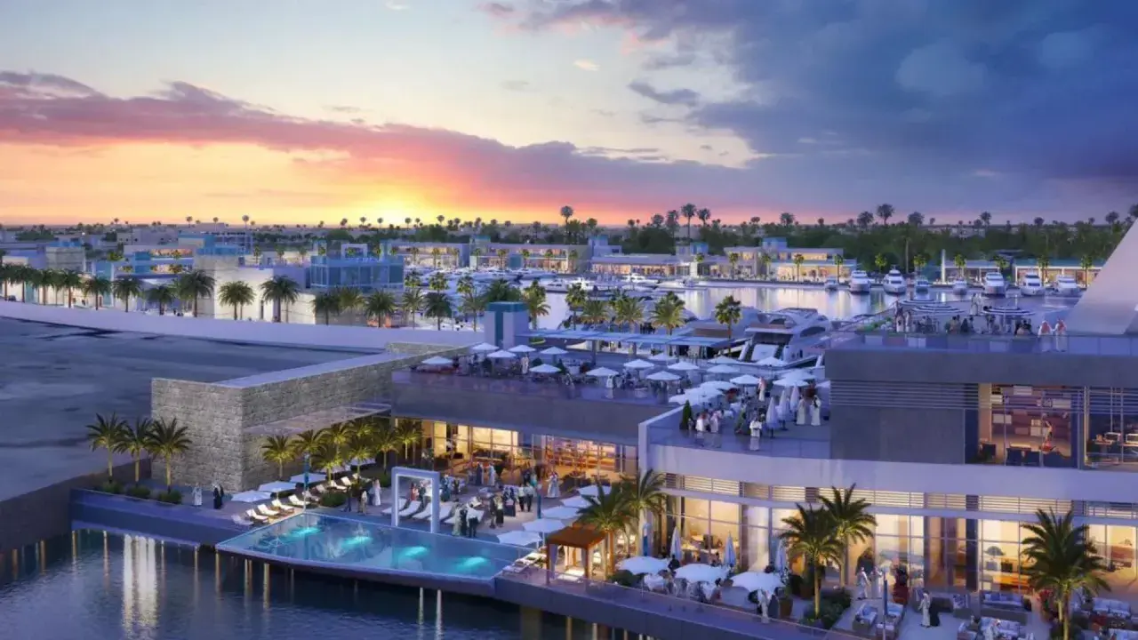 Un moderno complesso sul Jeddah port con piscina a sfioro, ristoranti all'aperto e yacht ormeggiati al tramonto.