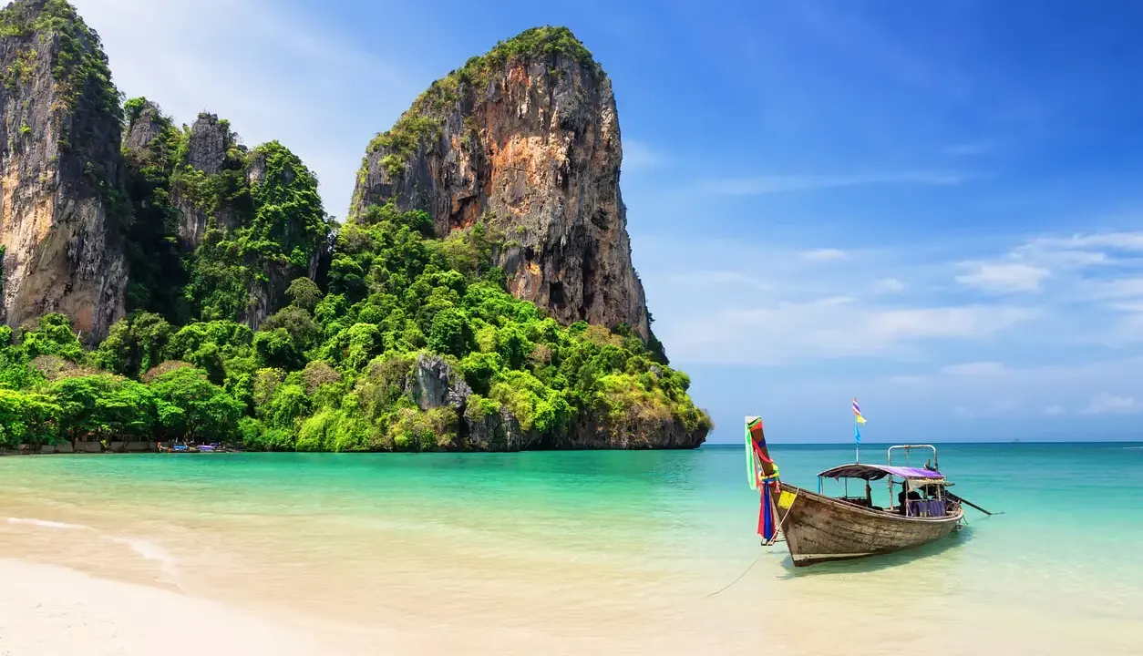 Idealna pogoda na Phuket w listopadzie: spokojne morze, piaszczysta plaża i tradycyjna łódź.