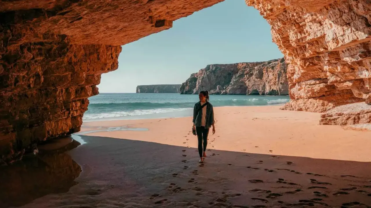 Frauen spazieren am Strand unter Felsbögen, ein perfekter Moment auf einer 14-tägigen Rundreise Portugal.
