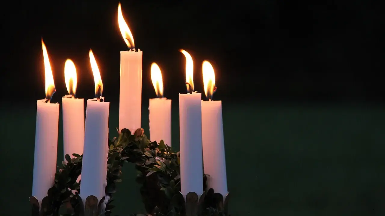 Sju ljus brinner i en krans, en påminnelse om vad betyder namnet Lucia: ljus.