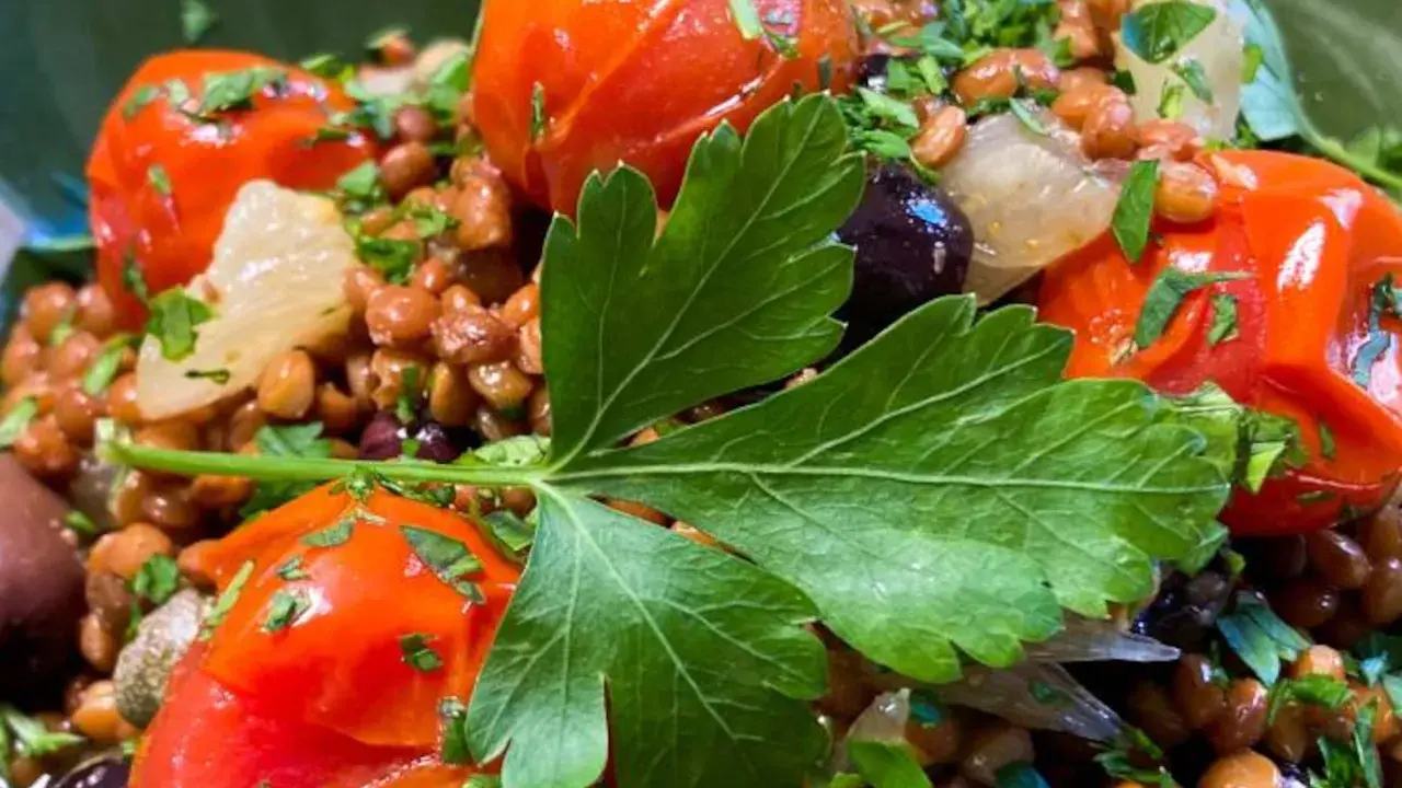 Ensalada de lentejas con tomates cherry, aceitunas negras y perejil fresco. Un plato saludable y lleno de sabor.