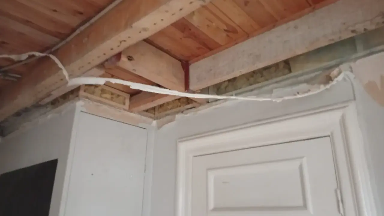 Taket och väggarna är under renovering. Man ser träbjälkar och isolering. För att kunna måla ordentligt har man valt att ta bort lister vid målning.