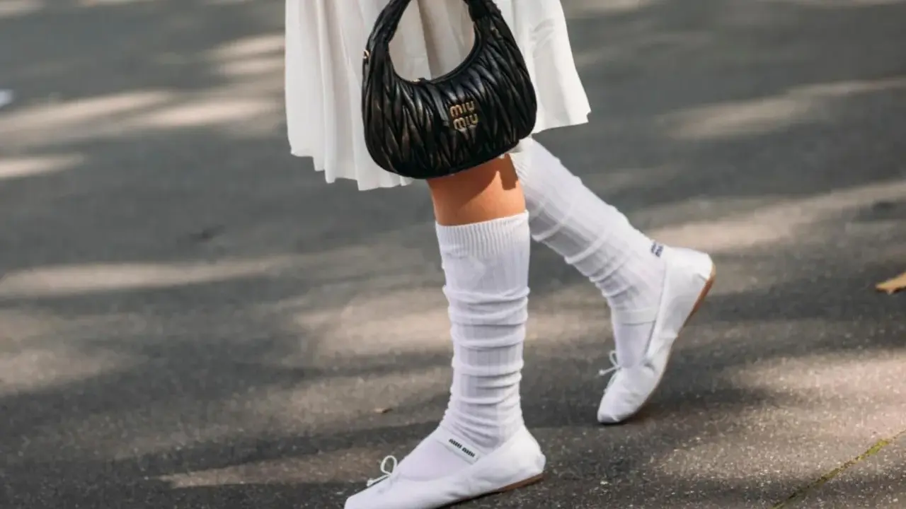 Piernas con bailarinas blancas y calcetines blancos arrugados, un look chic para bailarinas con calcetines.