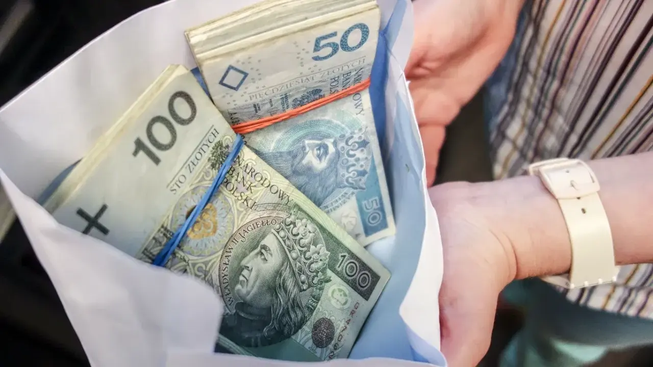 Koperta z plikiem banknotów 100 i 50 zł. Ile dać na 50 urodziny? Tyle pieniędzy to dobry prezent!