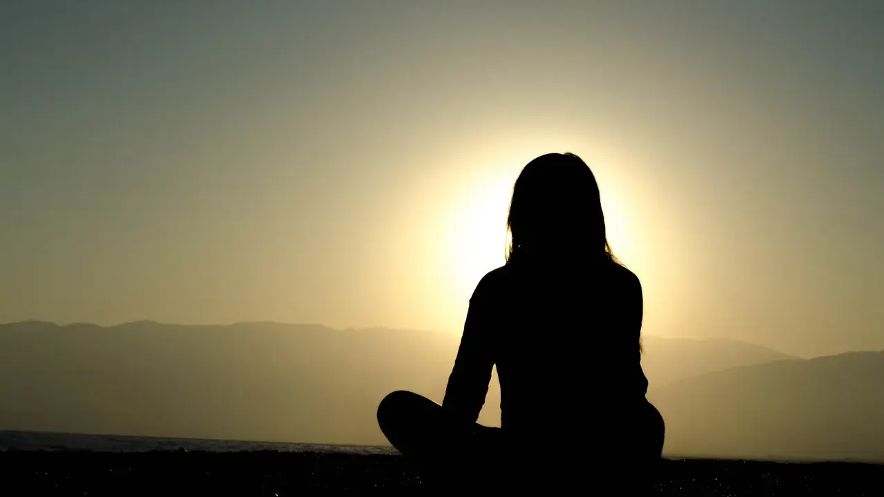 Silhuett av en person som mediterar vid solnedgången. Kanske är det en av nackdelar med meditation att man blir så fokuserad att man missar allt annat.