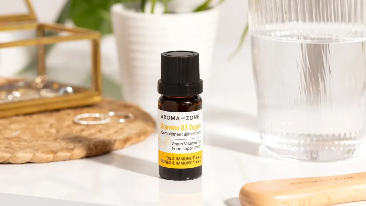 Un flacon de vitamine D3 vegan, un remède de grand-mère pour pallier le manque de vitamine D, à côté d'un verre d'eau.
