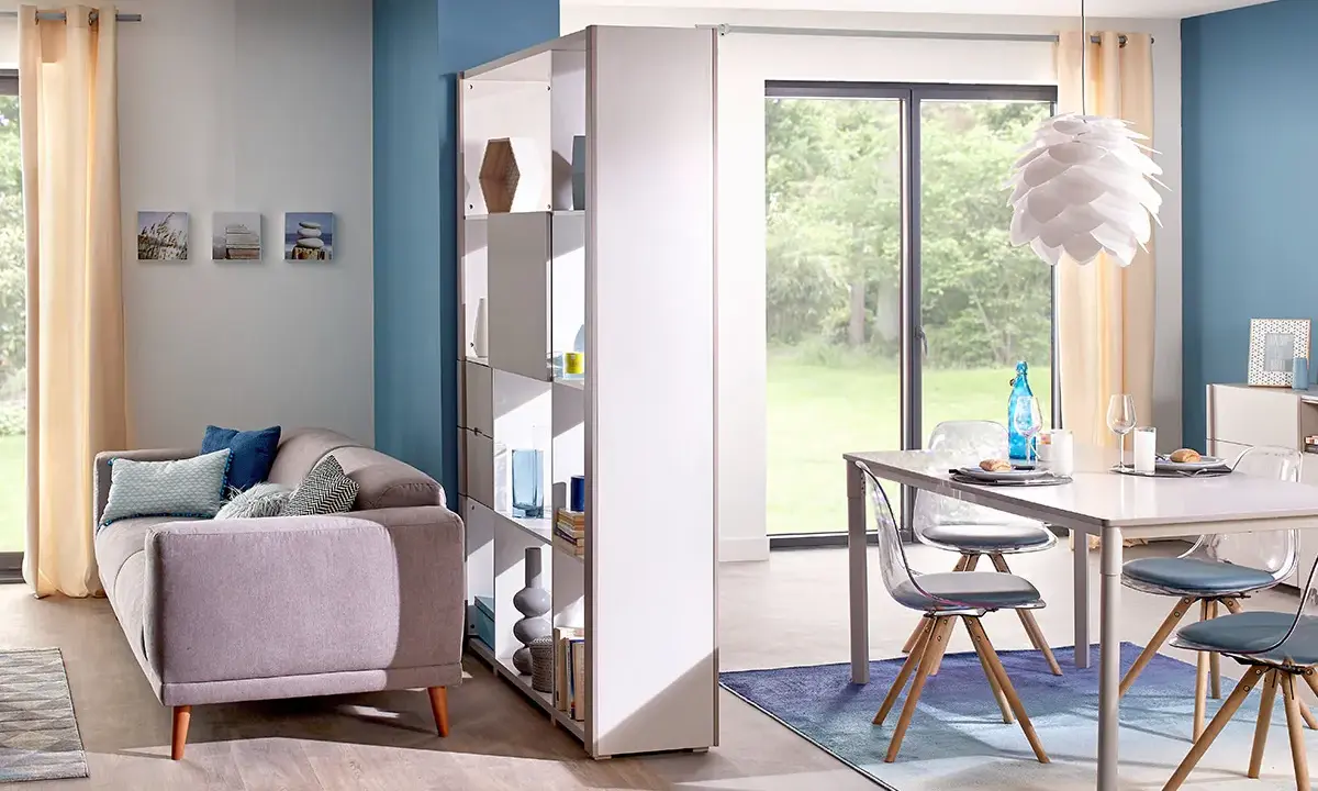 Aménagement salle à manger moderne avec canapé confortable et table design. Une étagère sépare les espaces.