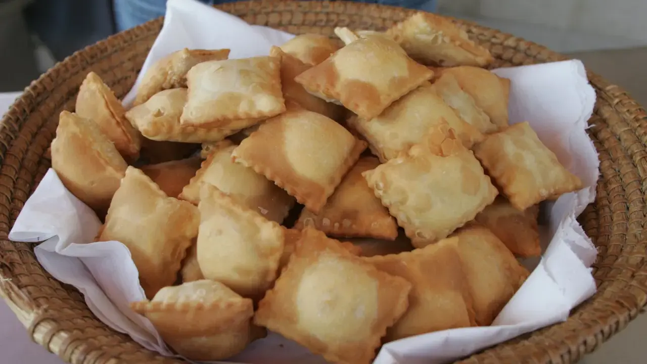 Un panier rempli de beignets dorés, une spécialité des Hautes-Alpes, prêts à être dégustés.
