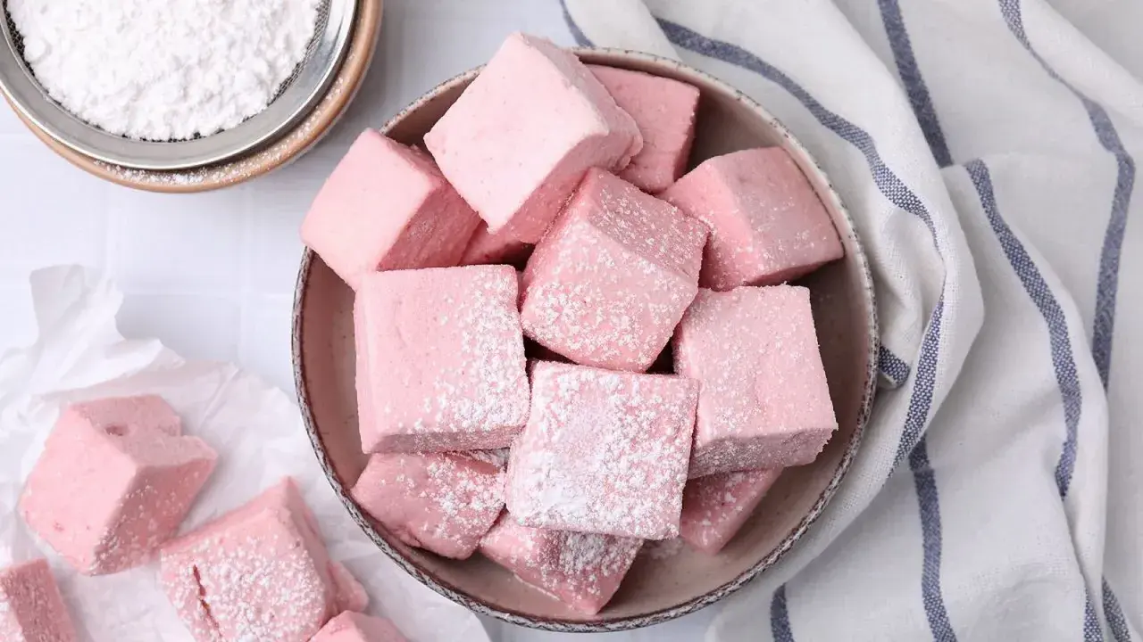 Dulces cubos rosados, como se hacen las nubes de azúcar, espolvoreados con azúcar glas.