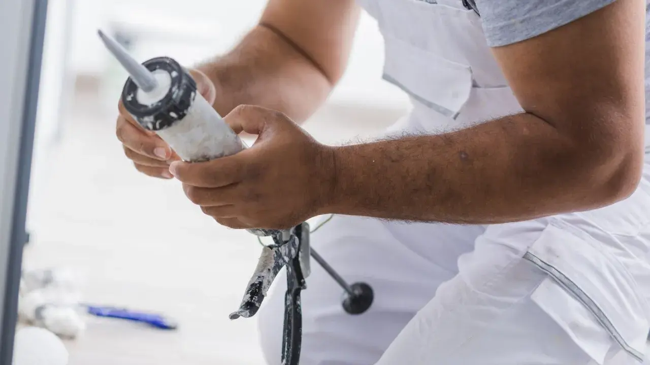 Un bricoleur prépare son pistolet à mastic pour une application. Il tient le tube de mastic Sika, prêt à l'emploi.