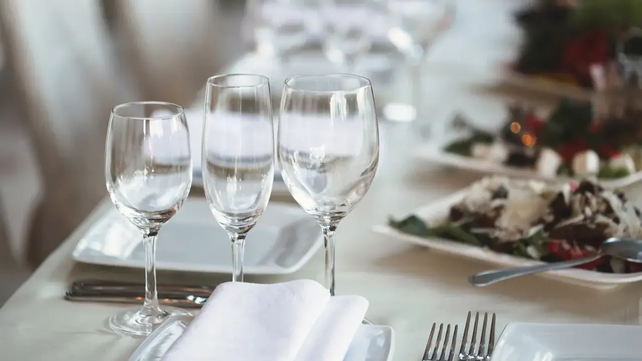 Trois verres à eau sont disposés sur une table dressée, prêts pour un repas.