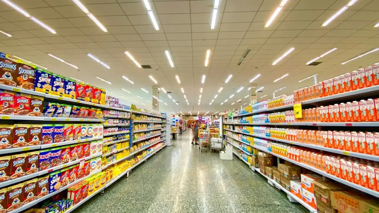 Alejka w supermarketach, pełna produktów na półkach. Widać kartony z płatkami śniadaniowymi i napojami. To typowe sklepy po angielsku, gdzie można znaleźć wszystko.