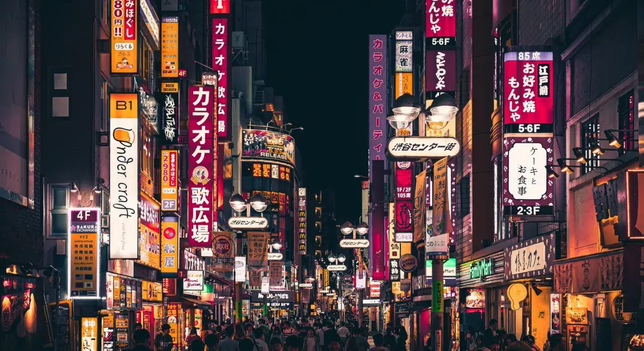 Nocne życie Tokio, neonowe szyldy zapraszają, kiedy do Japonii. Tłumy ludzi spacerują ulicami pełnymi barów i sklepów.