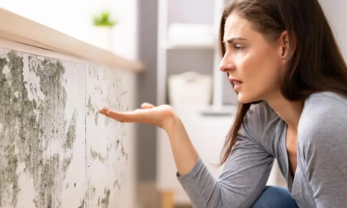 Donna preoccupata osserva muffa su muro, cercando soluzioni su come eliminare umidità in casa.