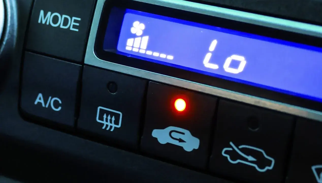 El aire acondicionado del coche muestra "Lo" indicando baja temperatura. El ventilador está al mínimo y la luz roja está encendida.