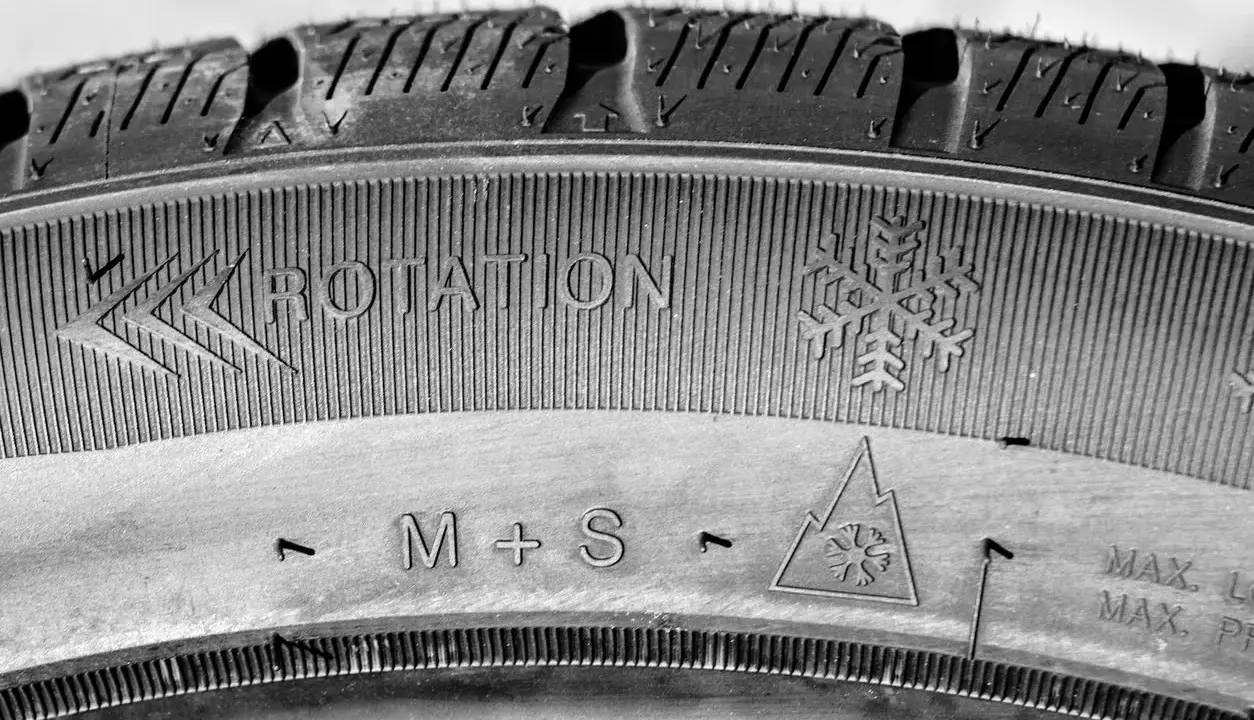 Neumático M+S con indicación de rotación y símbolo de copo de nieve, listo para el invierno.