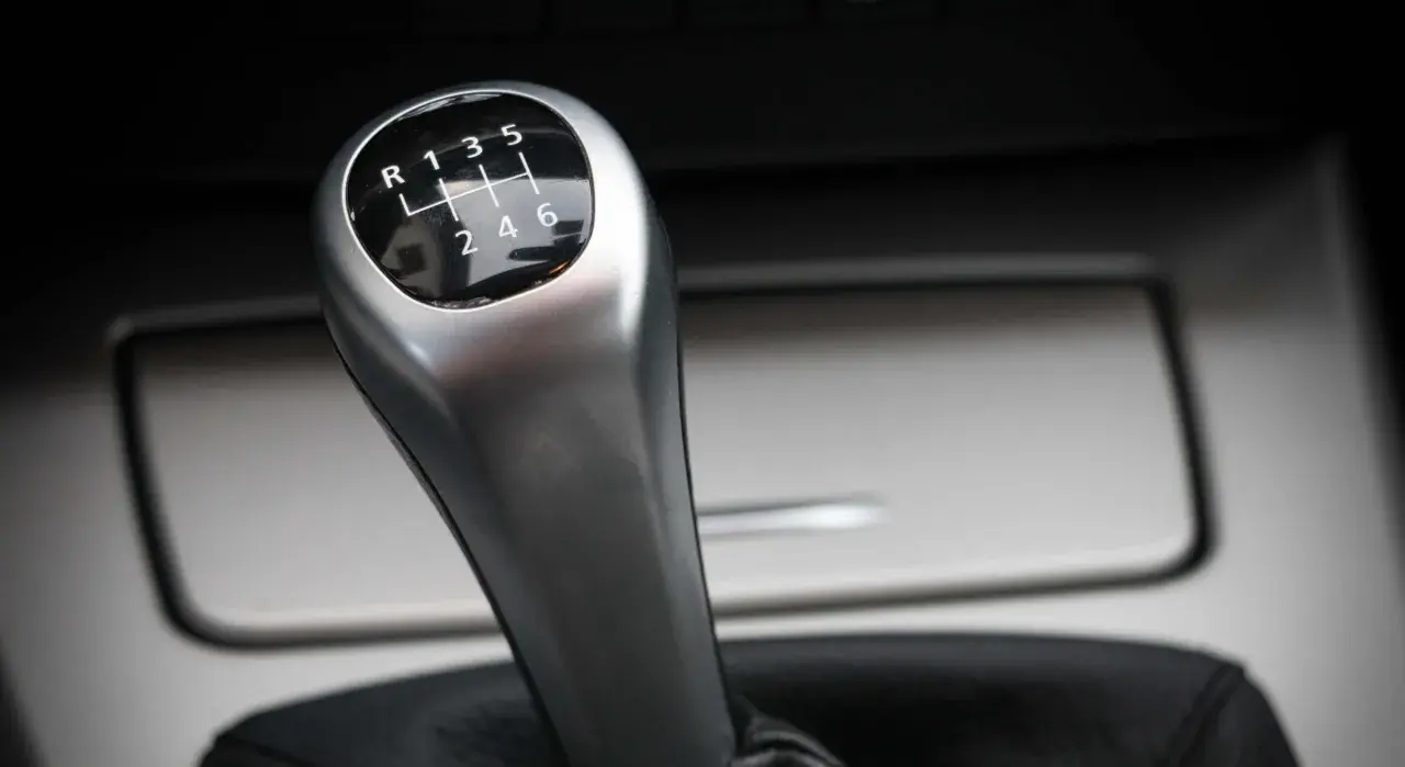 Palanca de cambios de un coche manual, con el patrón de marchas visible. Parece que el cambio de marchas roto impide seleccionar la marcha deseada.