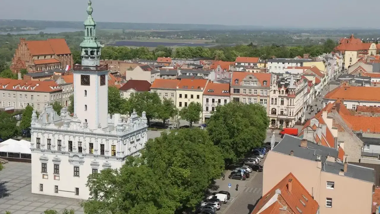 Widok na rynek w Chełmnie z ratuszem i wieżą. W tle kamienice i zieleń, idealne chełmno atrakcje.