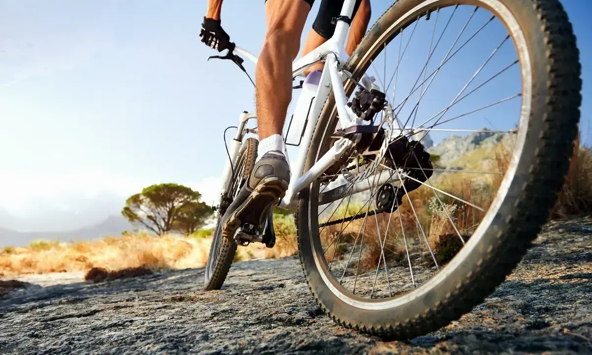 Kolarz na rowerze crossowym lub trekkingowym pokonuje kamienistą ścieżkę w słoneczny dzień.