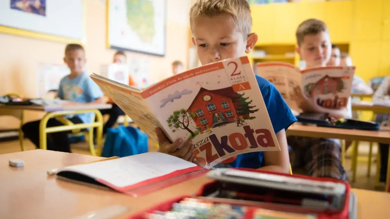 Chłopiec z zapałem czyta podręcznik "Nasza Szkoła". To dobry start dla każdego ucznia, by z radością poznawać świat.