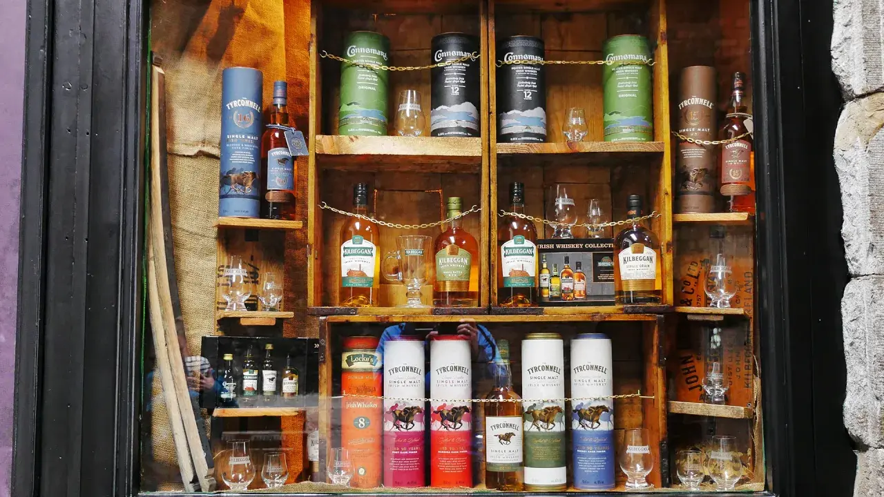 Regale voller irischer Whiskeys, darunter Connemara peated whisky, Kilbeggan und Tyrconnell. Gläser und Flaschen sind kunstvoll arrangiert.