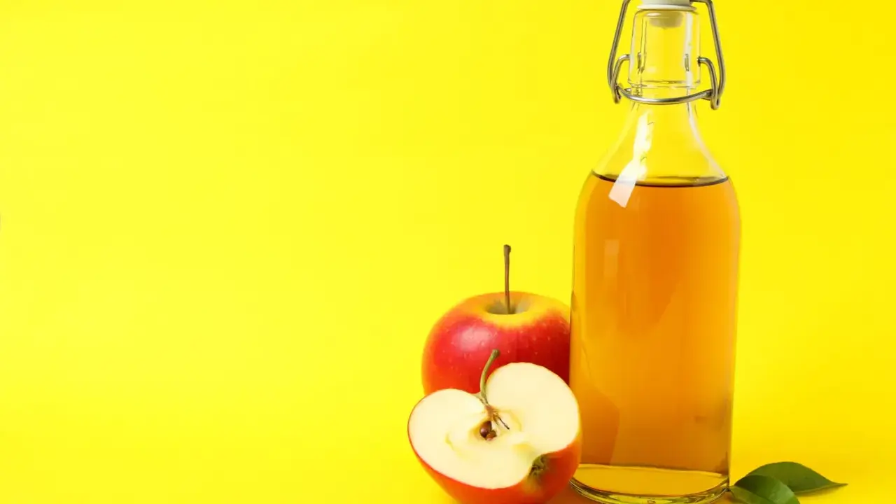 Bouteille de vinaigre de cidre et pommes rouges, un remède naturel pour l'urticaire.