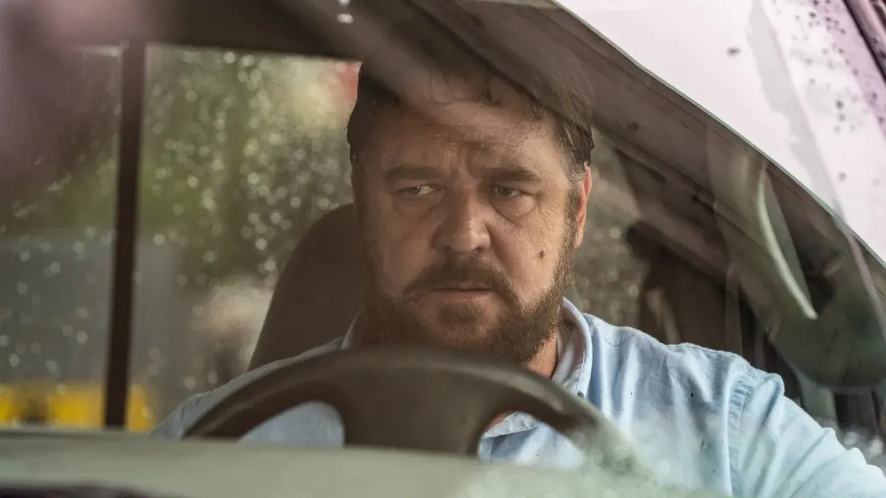 Russell Crowe bakom ratten i en bil, med regndroppar på vindrutan. En intensiv scen från filmer med Russell Crowe.