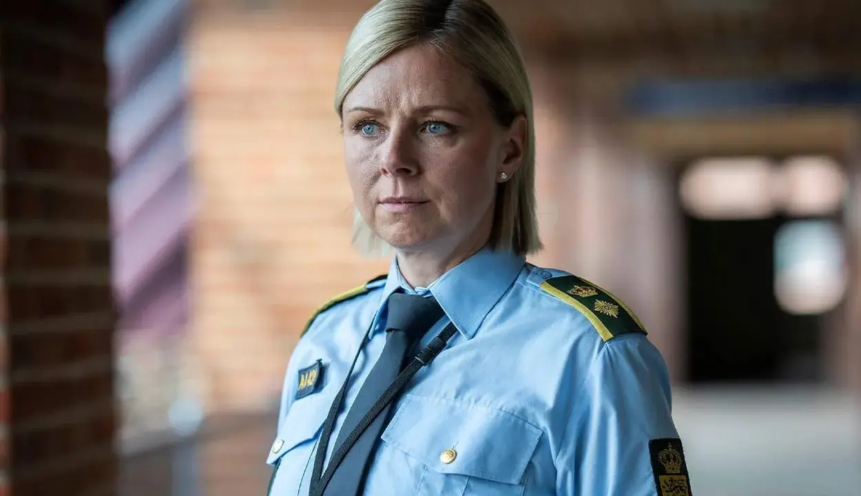 En kvinna i uniform från uniformen serie, med blå skjorta och slips, blickar ut.