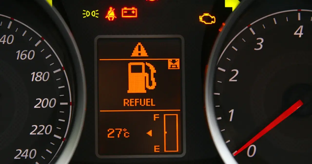 Na desce rozdzielczej świeci się kontrolka paliwa z napisem "REFUEL". Wskaźnik pokazuje niski poziom paliwa, sugerując, że rezerwa ile km zostało do przejechania jest niewielka.