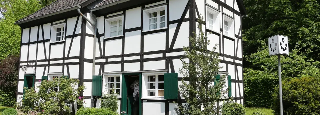 Ein liebevoll saniertes Fachwerkhaus mit grünen Fensterläden und üppiger Bepflanzung.