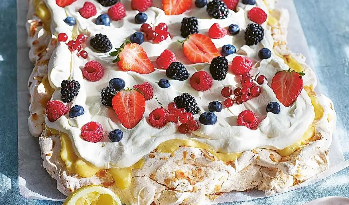 En stor pavlova med grädde och färska bär, perfekt för påskfirandet.