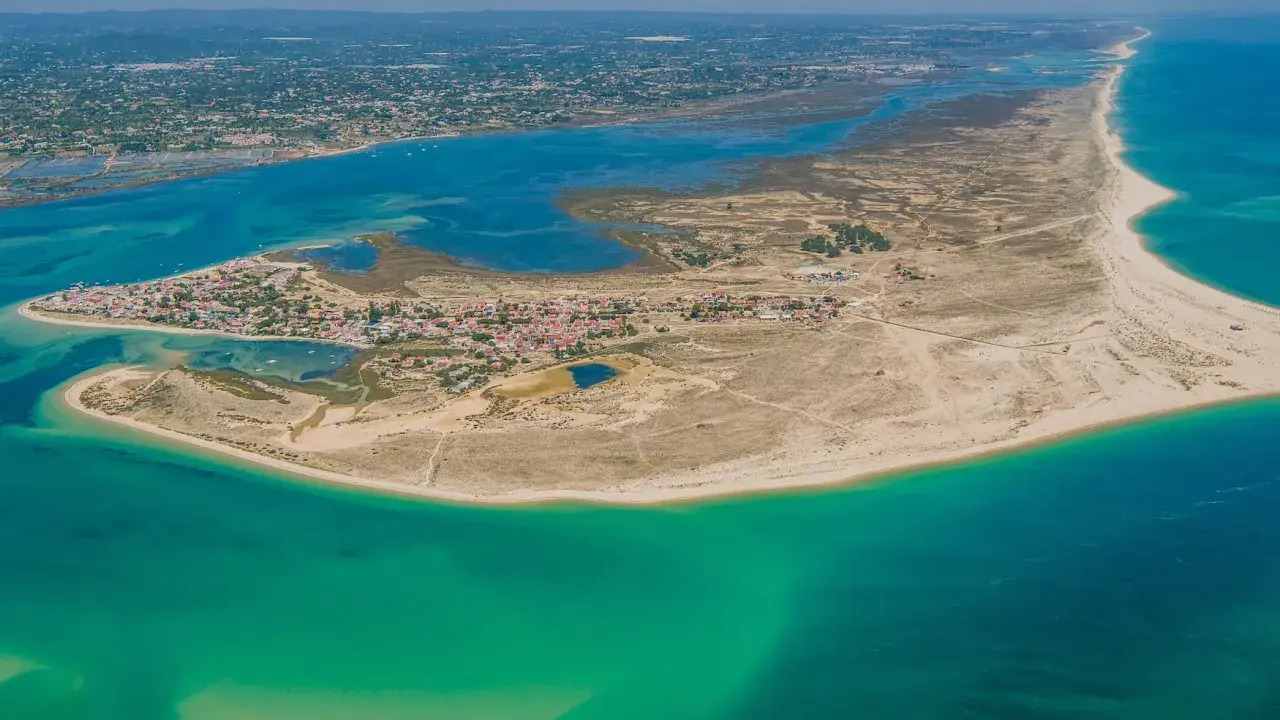 Luftaufnahme der Faro Inseln mit türkisfarbenem Wasser, Sandstränden und einer kleinen Stadt.
