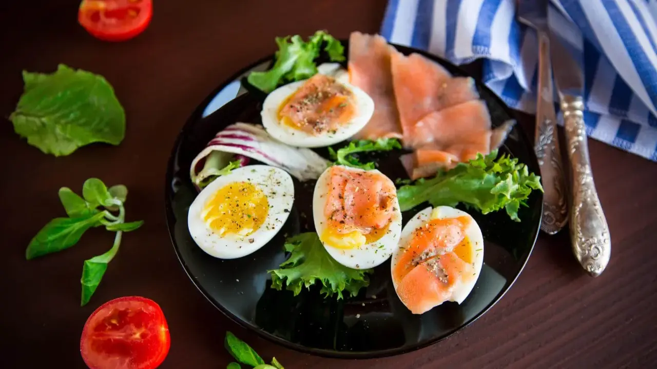 Jajka na twardo z łososiem i sałatą, idealne na dietę low carb. Pomidorki i zielenina dopełniają danie.