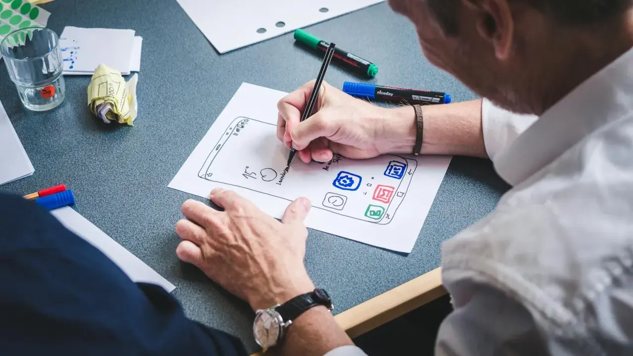 UX designer szkicuje interfejs aplikacji na papierze.
