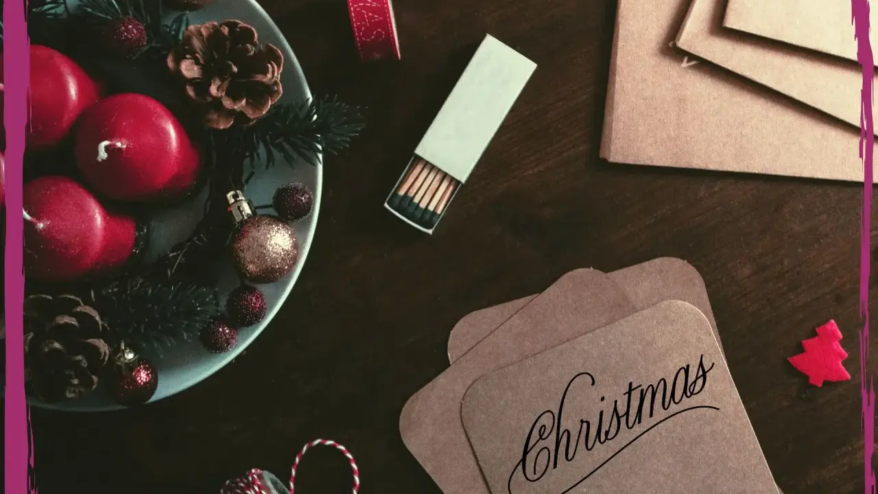 Candele rosse, pigne e decorazioni natalizie su un tavolo scuro, pronte per scrivere una poesia di Natale per adulti.