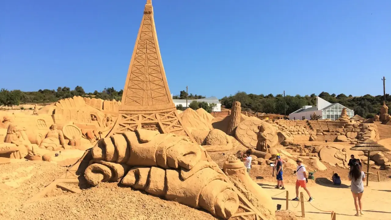 Beeindruckende Sandskulpturen, darunter der Eiffelturm, im Sand City Algarve. Besucher bestaunen die Kunstwerke.